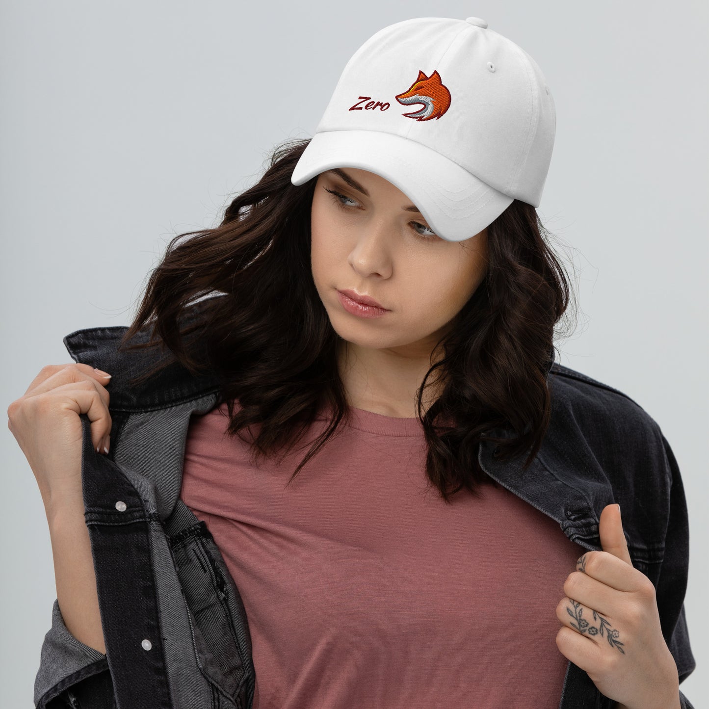 Woman wearing white baseball cap with embroidered fox and the word "Zero" on the front, suggesting the phrase "Zero Fox" or "Zero Fcks."