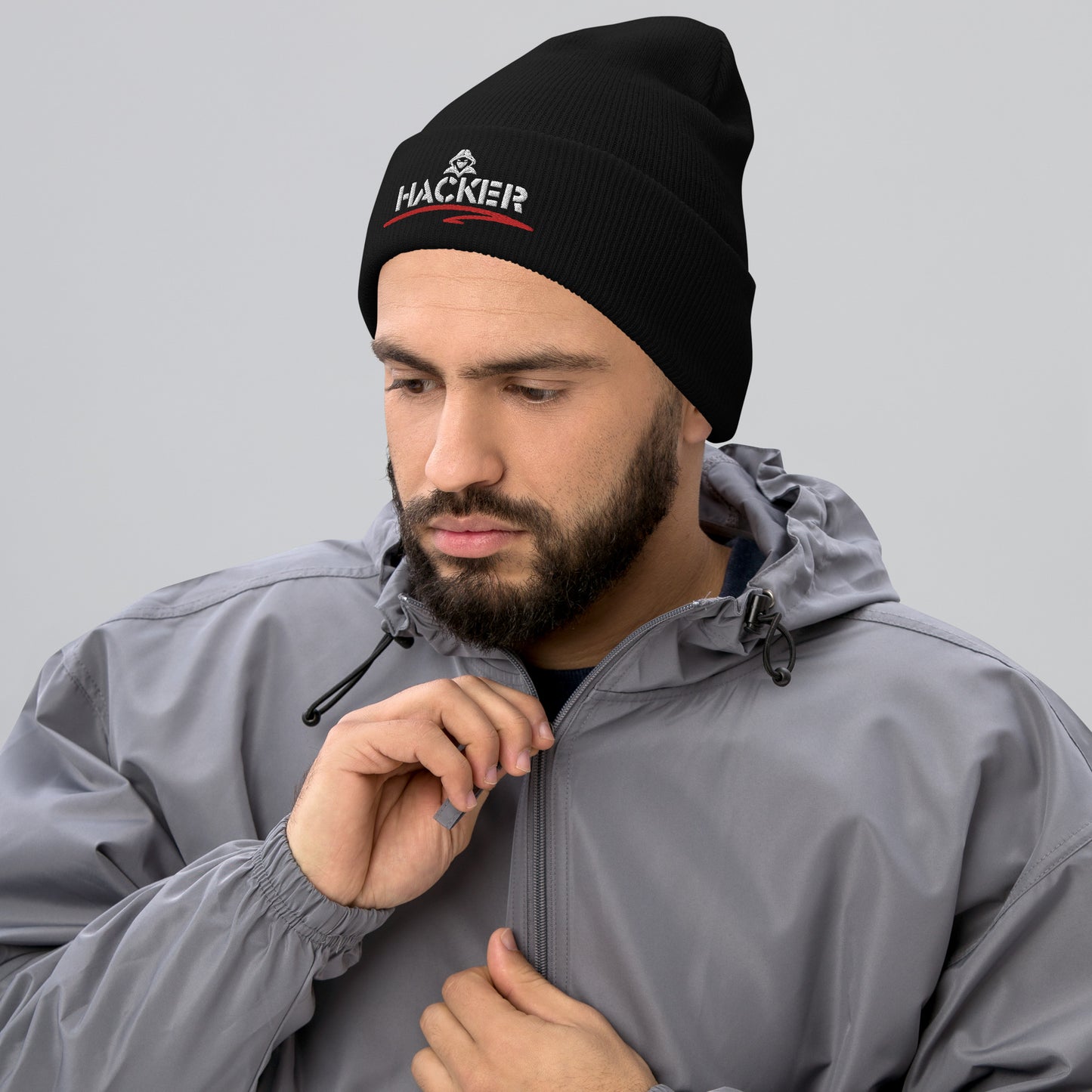 Man wearing a black beanie with the word 'HACKER' embroidered in bold white letters on the front.
