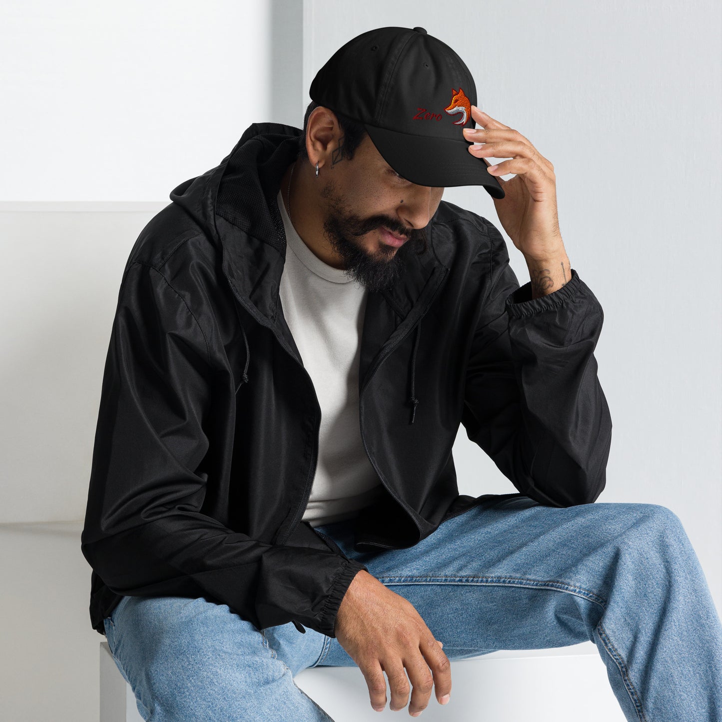 Man wearing black baseball cap with embroidered fox and the word "Zero" on the front, suggesting the phrase "Zero Fox" or "Zero Fcks."