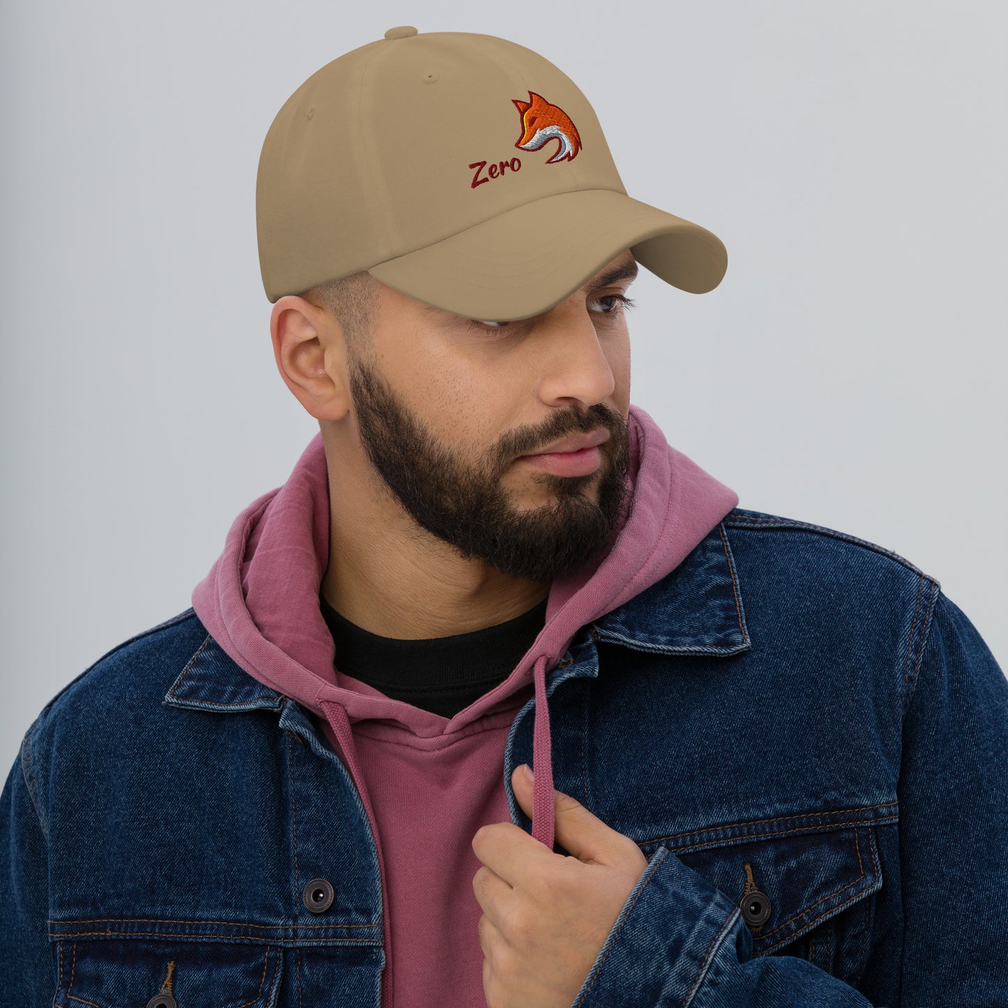 Man wearing khaki baseball cap with embroidered fox and the word "Zero" on the front, suggesting the phrase "Zero Fox" or "Zero Fcks."
