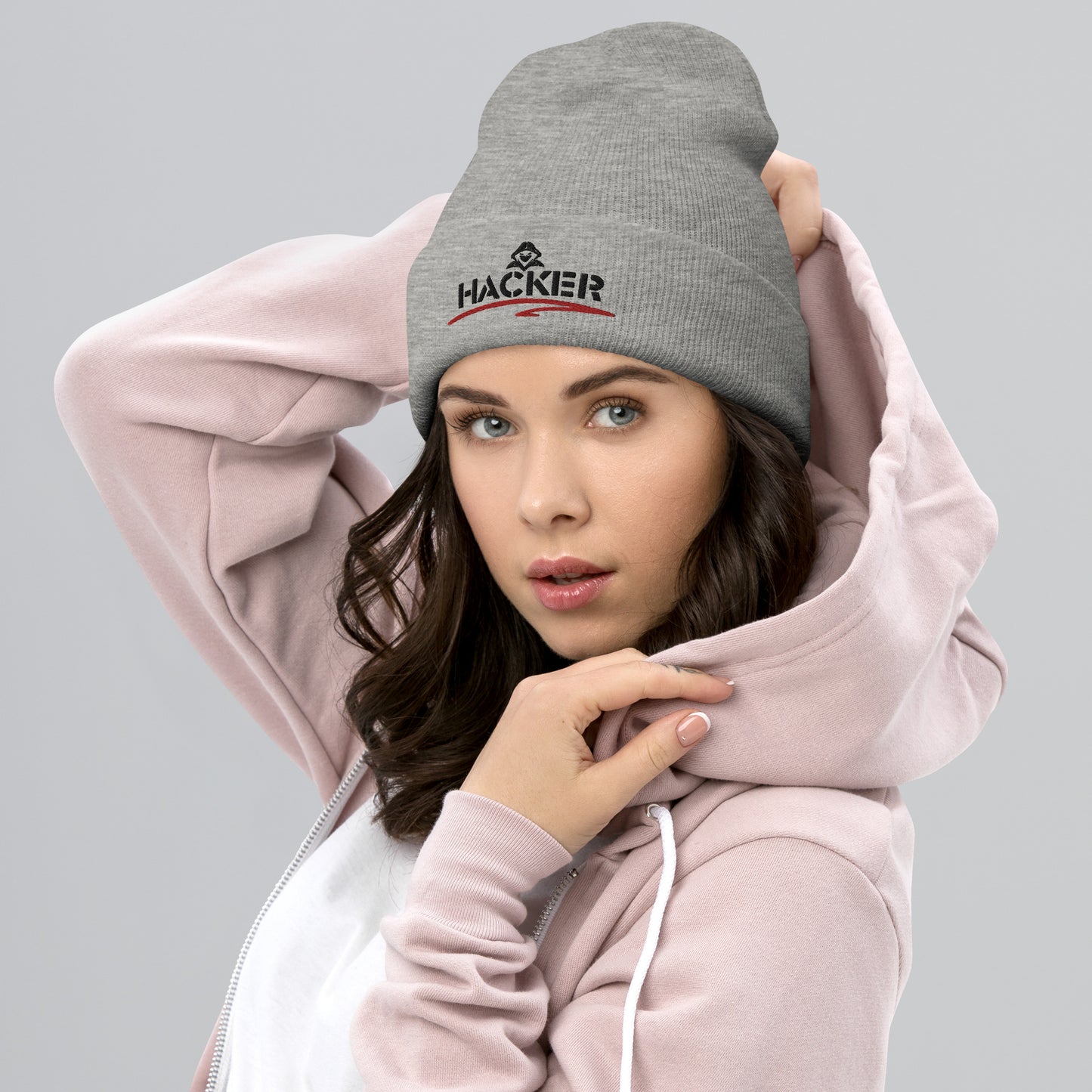 Woman wearing a heather grey beanie with the word 'HACKER' embroidered in bold black letters on the front.