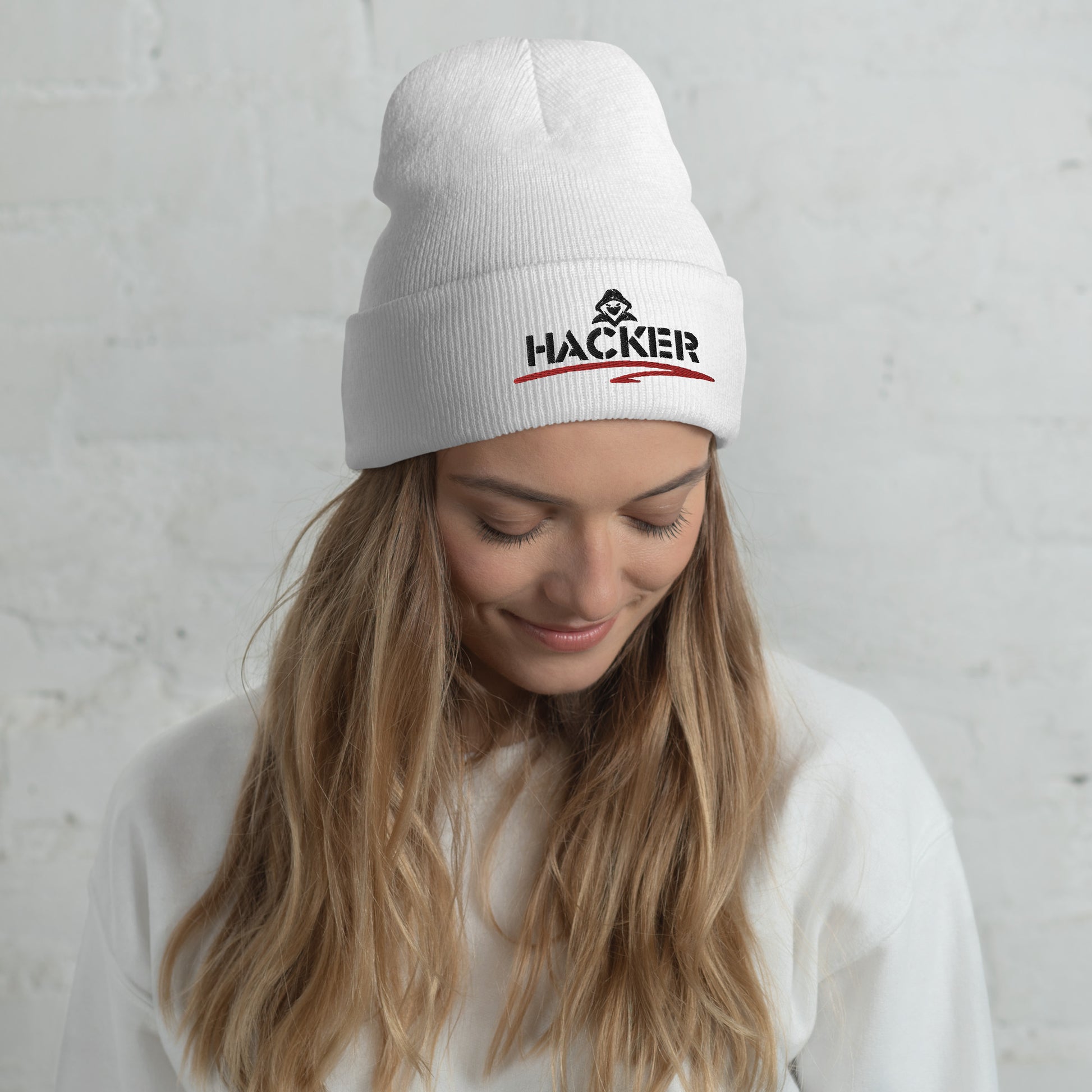 Woman wearing a white beanie with the word 'HACKER' embroidered in bold black letters on the front.